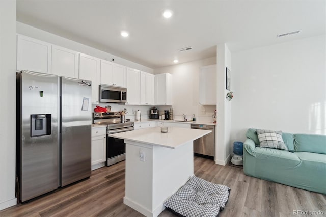 kitchen featuring appliances with stainless steel finishes, white cabinetry, wood-type flooring, sink, and a center island