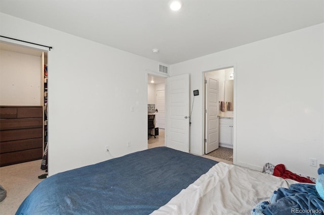 bedroom with connected bathroom and light colored carpet