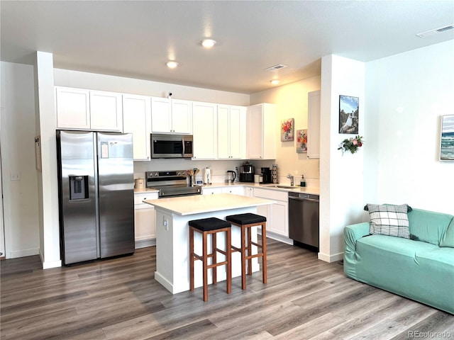 kitchen featuring visible vents, stainless steel appliances, wood finished floors, and a center island