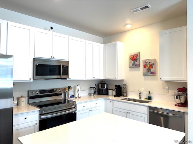 kitchen featuring stainless steel appliances, a sink, visible vents, white cabinets, and light countertops