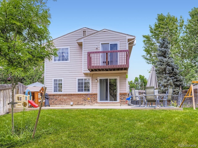 4904 E 125th Ave, Thornton, CO 80241 - back of house featuring a balcony, brick siding, a fenced backyard, and a playground