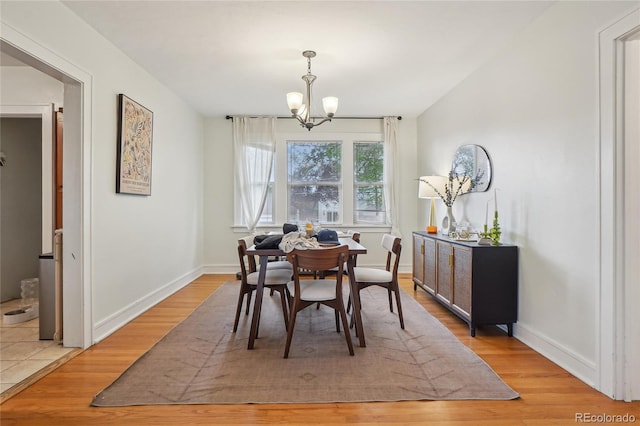 dining space with a chandelier, light wood-style flooring, and baseboards