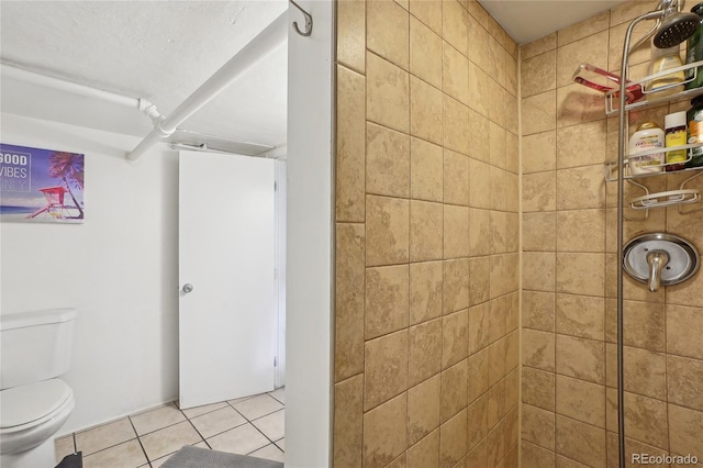 bathroom with tile patterned flooring, tiled shower, and toilet