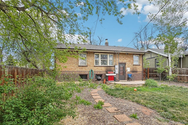 back of property featuring brick siding, a chimney, a fenced backyard, and a patio