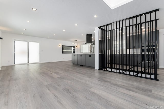 unfurnished living room with light wood finished floors, baseboards, and recessed lighting