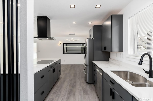 kitchen with modern cabinets, decorative light fixtures, range hood, stainless steel appliances, and a sink