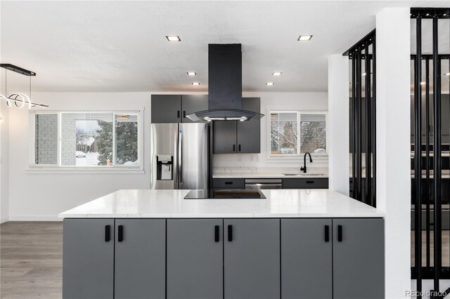 kitchen with pendant lighting, stainless steel appliances, gray cabinets, a sink, and island range hood