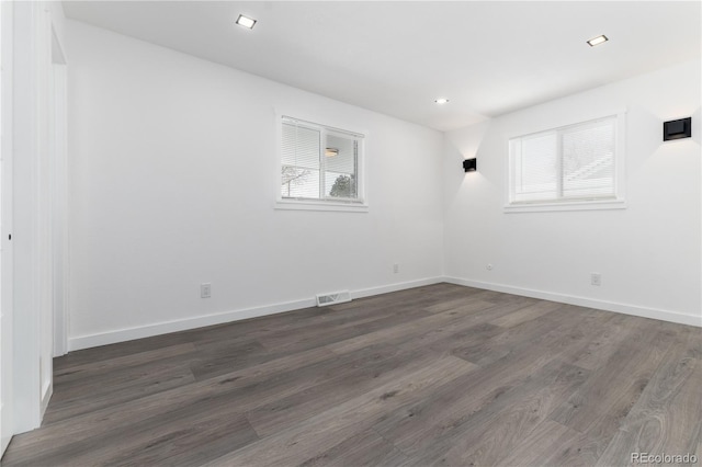 unfurnished room featuring dark wood-type flooring, plenty of natural light, and baseboards