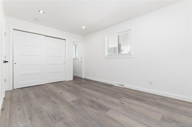 unfurnished bedroom with light wood finished floors, baseboards, visible vents, a closet, and recessed lighting