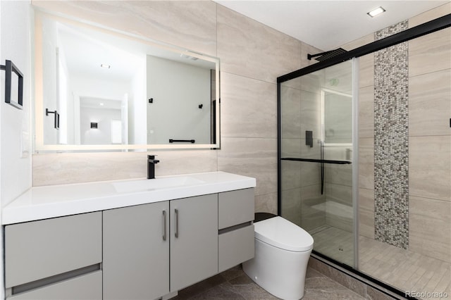 full bath with toilet, a shower stall, tile walls, and vanity