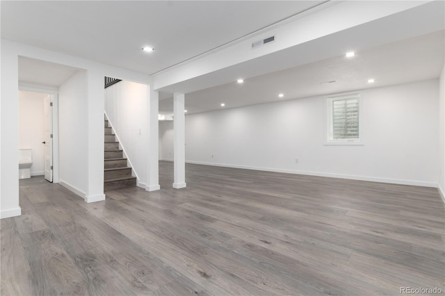 finished below grade area featuring stairway, visible vents, wood finished floors, and recessed lighting