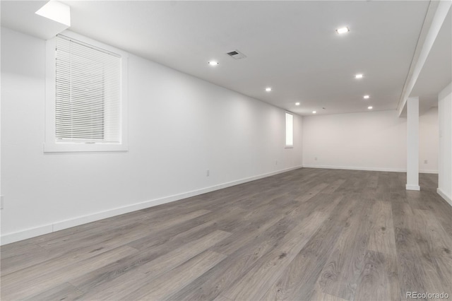 basement featuring baseboards, visible vents, wood finished floors, and recessed lighting