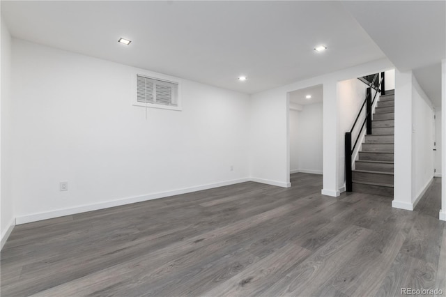 finished basement with baseboards, stairs, visible vents, and dark wood-style flooring