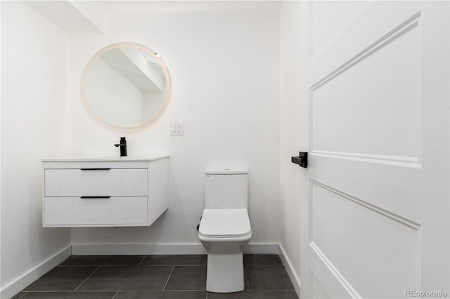 bathroom with toilet, tile patterned flooring, baseboards, and vanity