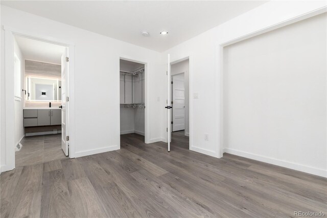 5886 S Logan St, Centennial, CO 80121 - unfurnished bedroom featuring wood finished floors, a closet, a walk in closet, baseboards, and ensuite bath