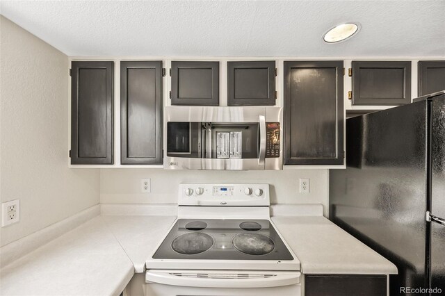 12099 Forest St, Thornton, CO 80241 - kitchen with white range with electric cooktop, freestanding refrigerator, stainless steel microwave, light countertops, and a textured ceiling