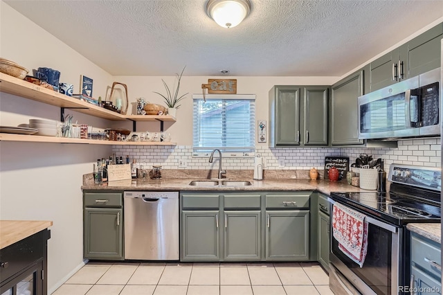 kitchen with a textured ceiling, appliances with stainless steel finishes, light tile patterned flooring, and sink