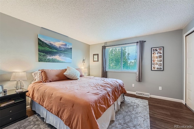 bedroom featuring a textured ceiling and dark hardwood / wood-style floors