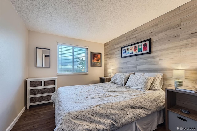 bedroom featuring a textured ceiling, wooden walls, and dark hardwood / wood-style floors