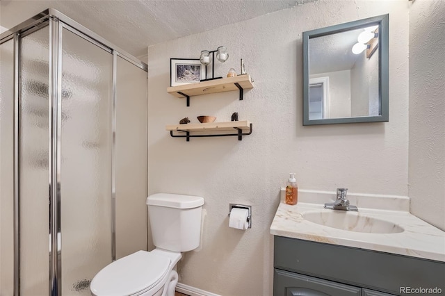 bathroom featuring a textured ceiling, a shower with door, vanity, and toilet