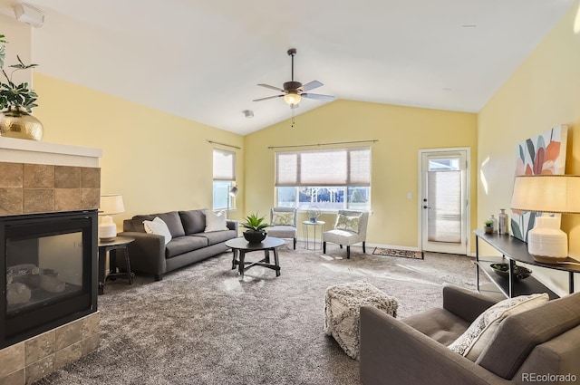 living room with carpet flooring, a tiled fireplace, ceiling fan, and vaulted ceiling