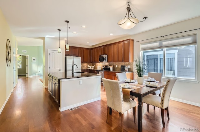 kitchen with hanging light fixtures, appliances with stainless steel finishes, and hardwood / wood-style floors