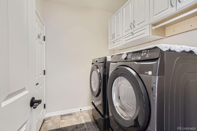 laundry room featuring washing machine and dryer, cabinets, and light tile patterned floors