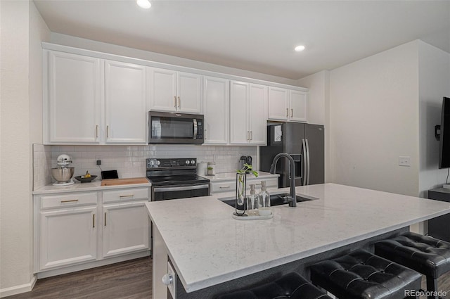 6027 N Netherland Ct, Aurora, CO 80019 - kitchen featuring black electric range oven, stainless steel microwave, fridge with ice dispenser, a kitchen island with sink, and white cabinetry