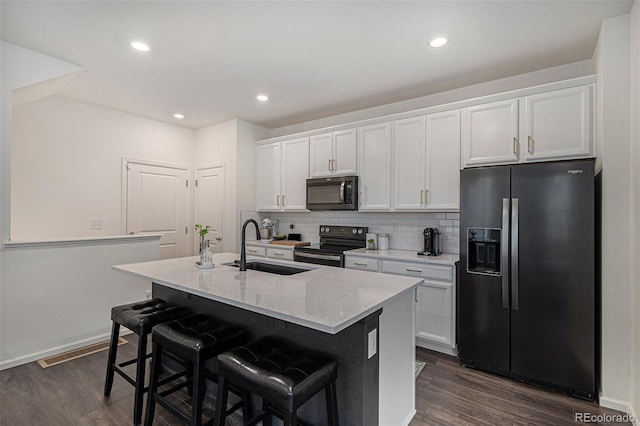 6027 N Netherland Ct, Aurora, CO 80019 - kitchen with black appliances, a center island with sink, dark wood-type flooring, white cabinets, and recessed lighting