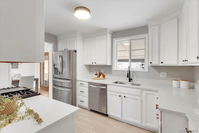 kitchen with light countertops, white cabinets, appliances with stainless steel finishes, and a sink