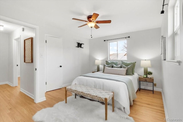 bedroom with baseboards, light wood-style floors, and a ceiling fan