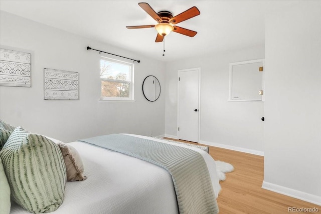 bedroom with baseboards, light wood-style floors, and a ceiling fan