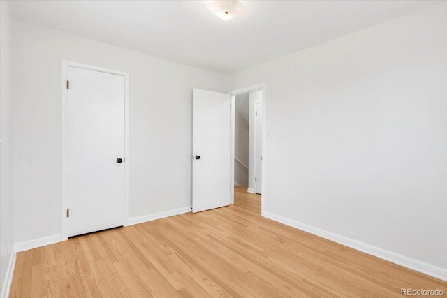 unfurnished bedroom with a closet, baseboards, and light wood-style floors