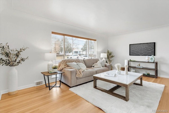 living room featuring visible vents, light wood-type flooring, and baseboards