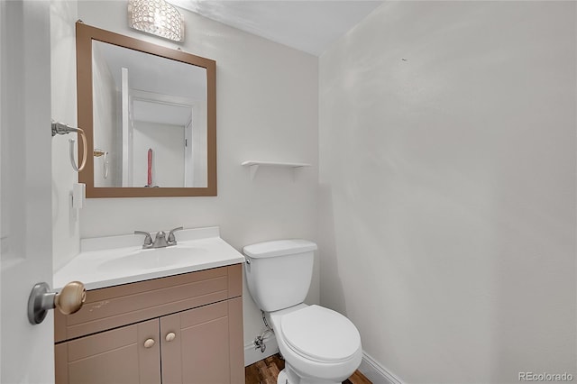 3615 Birnamwood Dr, Colorado Springs, CO 80920 - half bathroom with vanity, toilet, wood finished floors, and baseboards