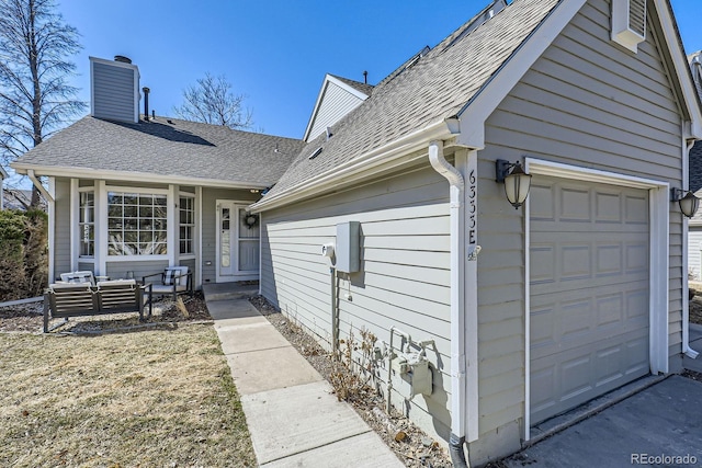 entrance to property with an attached garage, a chimney, an outdoor hangout area, and roof with shingles