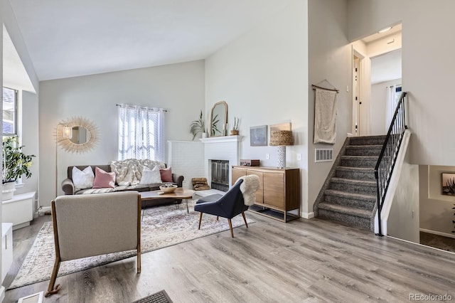 living area with light wood finished floors, stairs, high vaulted ceiling, and a wealth of natural light