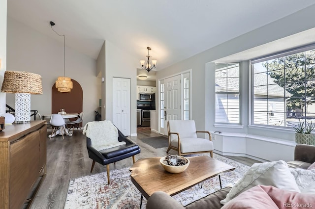 living room with an inviting chandelier, high vaulted ceiling, and wood finished floors