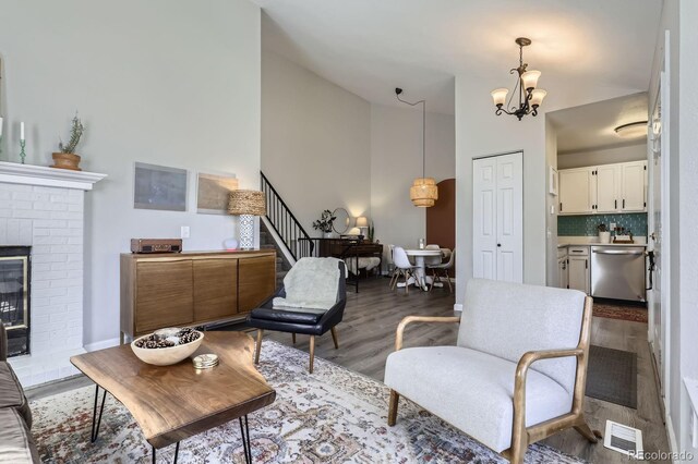 living area with visible vents, stairway, wood finished floors, a fireplace, and a notable chandelier