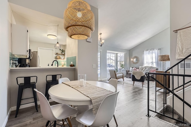 dining room with lofted ceiling, baseboards, stairway, and wood finished floors