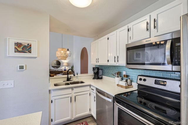 kitchen with white cabinets, backsplash, stainless steel appliances, and a sink