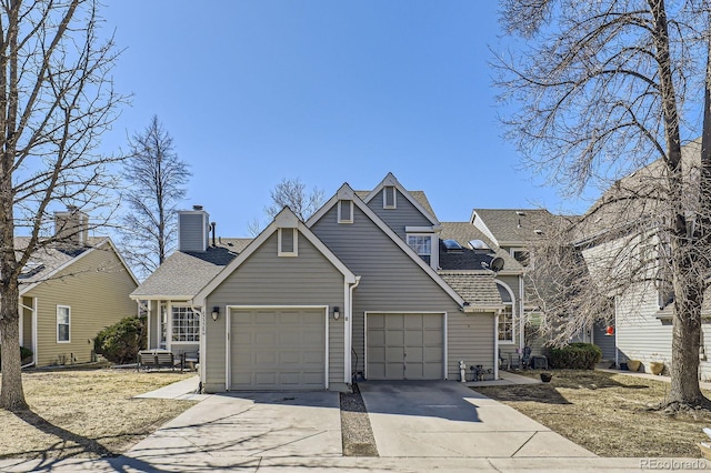 view of front of home with a shingled roof, concrete driveway, a chimney, an attached garage, and central AC