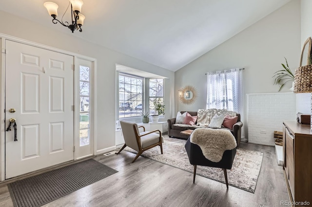 foyer entrance with plenty of natural light, an inviting chandelier, and wood finished floors