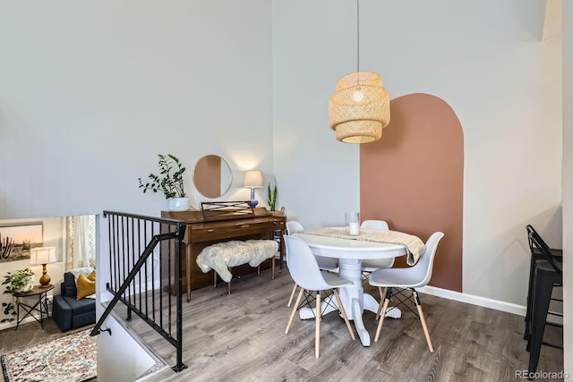 dining space featuring baseboards, arched walkways, and wood finished floors