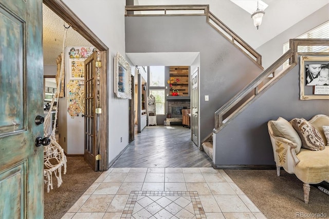 1744 Brookside Dr, Highlands Ranch, CO 80126 - entrance foyer featuring inlaid floor details, stairway, a fireplace, tile patterned flooring, and a towering ceiling