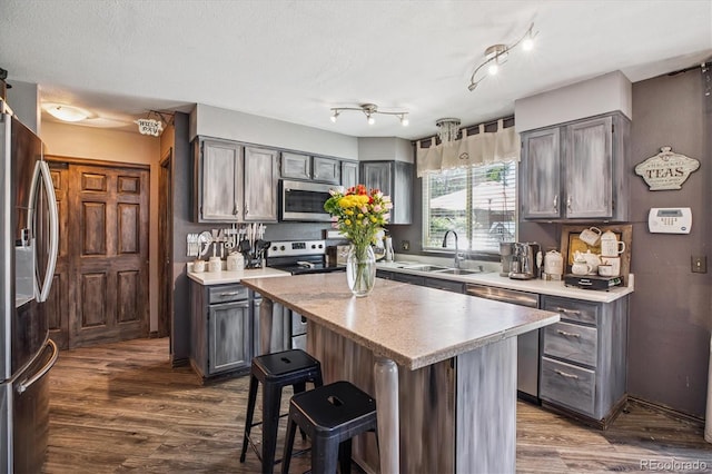 1744 Brookside Dr, Highlands Ranch, CO 80126 - kitchen with appliances with stainless steel finishes, a kitchen bar, light countertops, dark wood-type flooring, and a center island