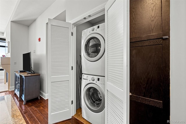 washroom with stacked washer and dryer and dark hardwood / wood-style flooring