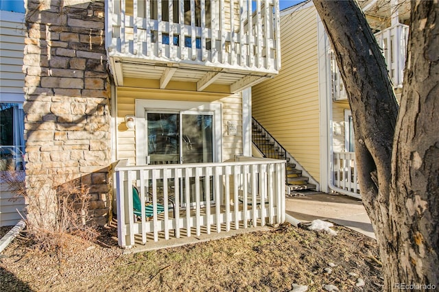 entrance to property featuring stone siding and a balcony