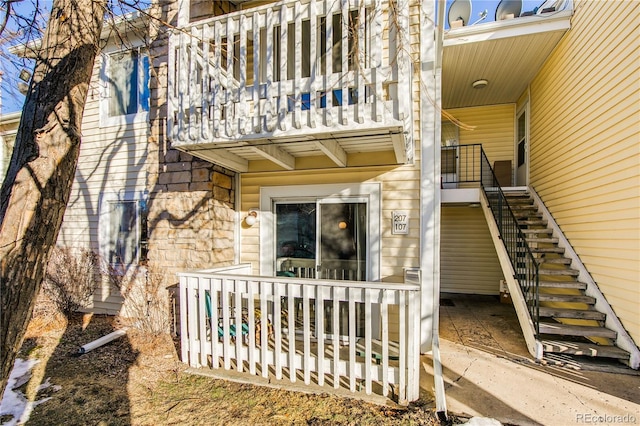 property entrance featuring stone siding and a balcony