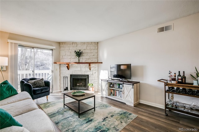 living area featuring dark wood-style flooring, visible vents, a fireplace, and baseboards